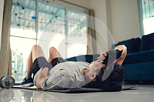 Young man take a break while exercises on yoga mat in living room at home