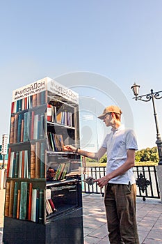 Young man takes books from a free book exchange point. Rostov-on-Don, Russia, august 07 2021