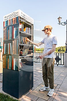 Young man takes books from a free book exchange point. Rostov-on-Don, Russia, august 07 2021