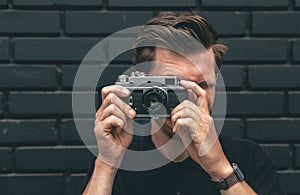 A young man takes a photo with a vintage film camera.