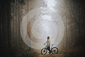 Young man taking a brake during biking through autumn forest