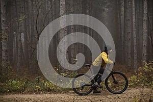 Young man taking a brake during biking through autumn forest