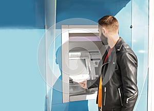 Young man taking money from cash machine