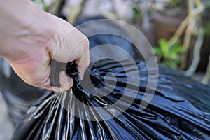 Young man taking out garbage in black plastic bag