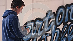 Young man taking photo of his wall graffiti on the phone