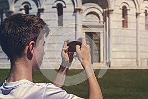 Young man taking a photo of the leaning tower of Pisa