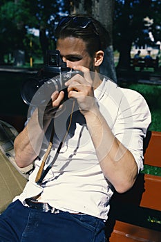 Young man taking a photo. Tourist photographs the city on green alley background.