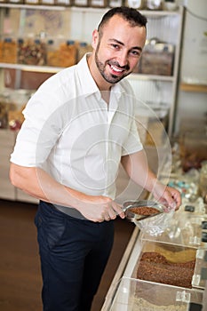 Young man taking with scoop cereals sold