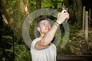 Young Man Taking Selfie with Cell Phone in Forest
