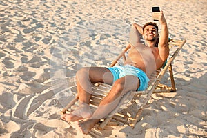 Young man taking selfie in  chair on beach