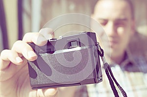 Young man taking a selfie with an old film camera, filtered