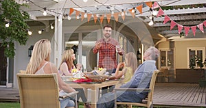 Young man taking to family members while having lunch outdoors