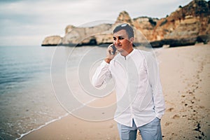 Young man is talk at his phone on beach in sunset