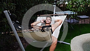 Young man talking on cellphone on hammock