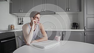 Young man talking on mobile phone at kitchen.