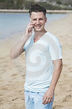 Young man talking on mobilephone at the beach