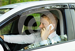 Young man talking on the phone behind the wheel of a car