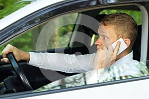 Young man talking on the phone behind the wheel of a car