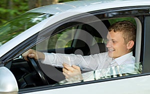 Young man talking on the phone behind the wheel of a car