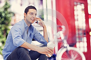 Young man talking phone and drinking coffee