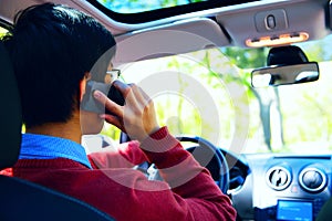 Young man talking on the phone and driving car