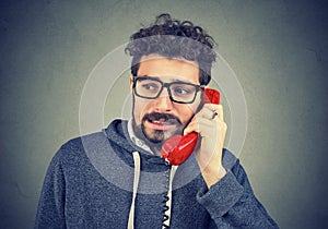 Young man talking on the phone, feeling awkward and embarrassed photo