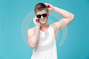 Young man talking on phone isolated over blue