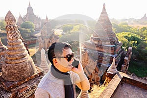 Young man talking on the phone in rural and temple pagoda area - can indicate good signal of telecommunication.