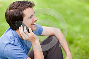 Young man talking on the phone while sitting on the grass