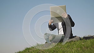 Young Man Talking On Skype Using a Laptop While Sitting On The Grass In The Park