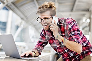 Young Man Talking Smartphone Browsing Laptop Concept