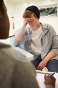 Young Man Talking To Counsellor Who Takes Notes