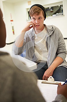 Young Man Talking To Counsellor Who Takes Notes