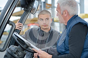 Young man talking to driver forklift