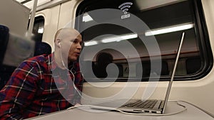 Young man talking on the video through the computer while on the train.