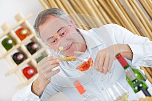 Young man tasting rose wine with cheese board