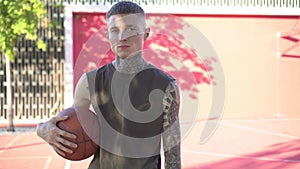 Young man with tattoos on the background of a basketball court. Modern youth image