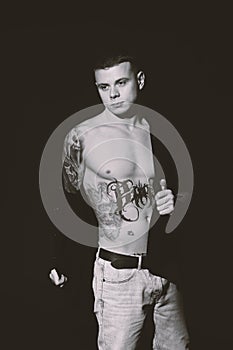 Young man with tattoos on dark background. Black and white photography