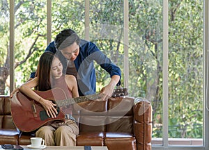 The young man teach his girlfriend to play a guitar