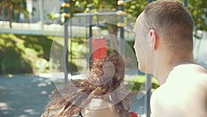 Young man teaches beautiful woman boxing blows outdoors at sunny day, slow-motion