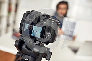 Young man teaching online, looking at camera and explaining new theme while working from home. Focus on camera photo
