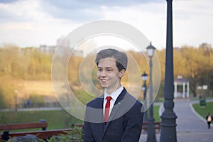 A young man, a teenager, in a classic suit. Walking along the avenues of the spring park. photo