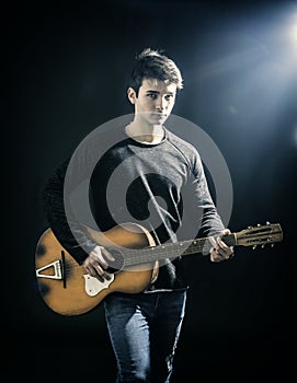 Young man or teenager playing guitar in studio