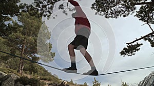 A young man teeters on a slackline in the mountains of the north Caucasus. Slackline en background of the mountains