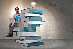 The young man in telelearning concept with laptop and books