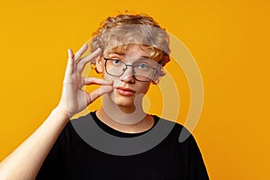 Young man telling to be quiet on yellow background in studio
