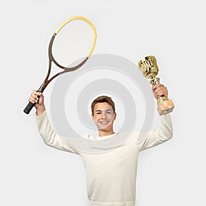 Young man with tennis racket and winner cup