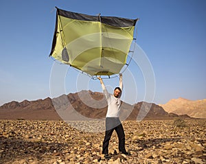 Young man with tent in desert landscape