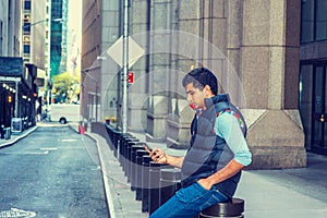 Young man texting on cell phone on street in New York City