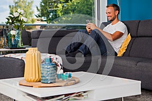 Young man texting with his phone on the couch